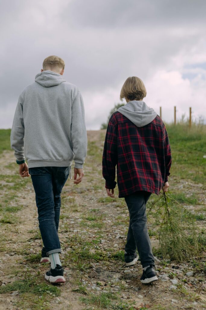 Two individuals walking on a gravel path outdoors, enjoying a peaceful day.